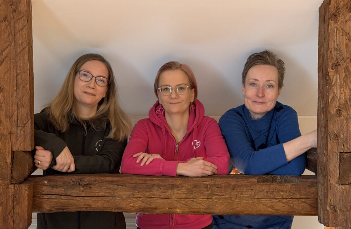 På bilden syns Mariehamns församlings diakon Kati Juntunen samt insamlingssbyrås medarbetare Katja Pääkkönen och Johanna Yli-Opas. Alla tre ler.